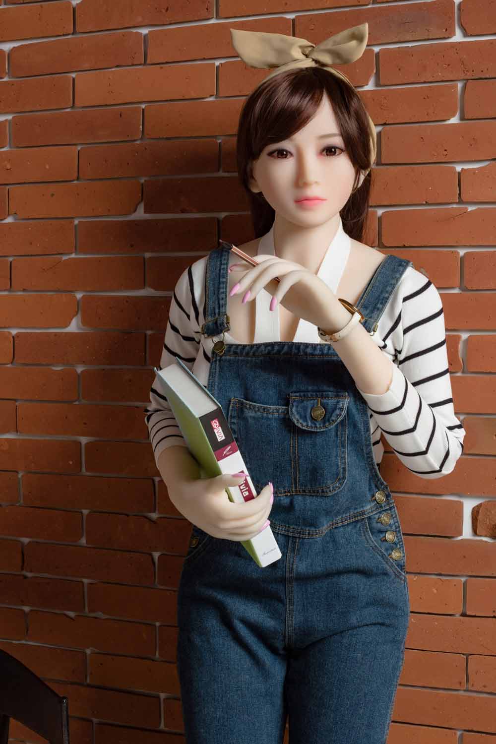 Sex doll with a book in one hand and a pen in one hand